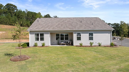 booth back exterior of model home with back concrete patio and large yard