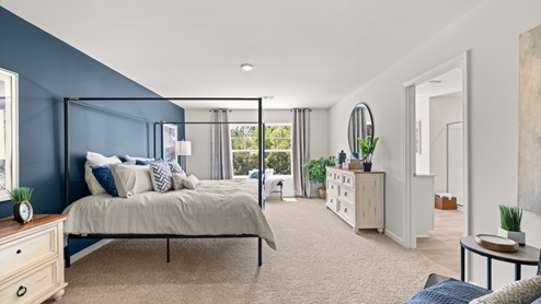 Interior primary bedroom with accent wall and large window