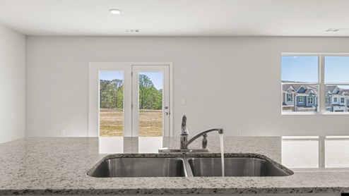 Kitchen island with sink, back doorm and a double window