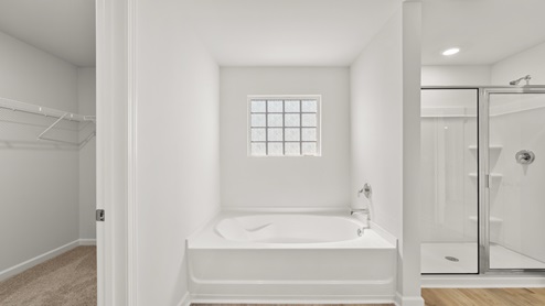 A bathroom with a tub, shower, and window