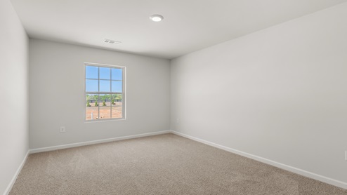 A bedroom with a window and carpet floors.