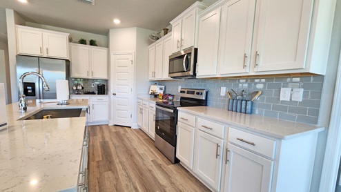 Kitchen with white shaker style cabinetry, stainless-steel appliances and corner pantry.