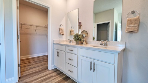 Double sink vanity with granite counters and door to wallk-in closet.