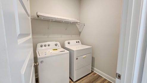 Laundry room with shelf above.