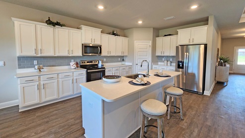 Granite countertop island with seating and white shaker cabinetry.