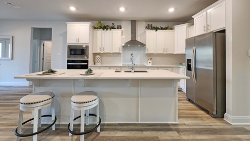 White shaker style cabinetry, with stainless-steel appliances and granite countertop island with seating.