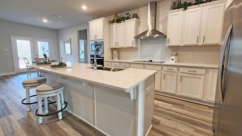Sleek kitchen with large breakfast bar, white cabinets, and LVP flooring in Mobile.