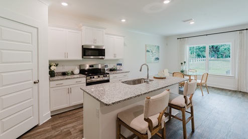 Kitchen and central peninsula with white cabinets and granite countertops and stainless-steel appliances.