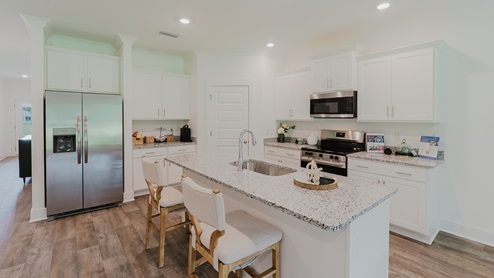 Kitchen and central peninsula with white cabinets and granite countertops and stainless-steel appliances.