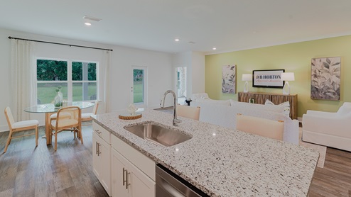 Kitchen and central peninsula with white cabinets and granite countertops and stainless-steel appliances.