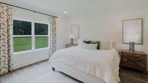 Spacious primary bedroom with two connected windows overlooking the backyard.