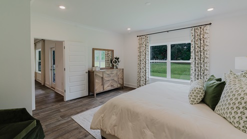 Spacious primary bedroom with two connected windows overlooking the backyard.