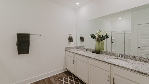 Primary bathroom with white cabinets, granite countertops, and double undermount sinks.