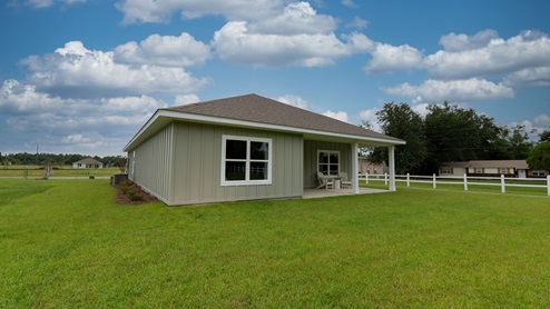 Covered back porch with neutral-green board and batten, two columns, and a spacious backyard.