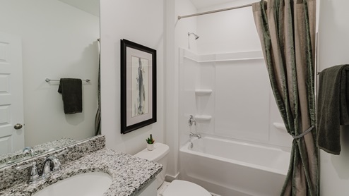 Secondary bathroom with white cabinets, granite countertops, and shower and tub combination.