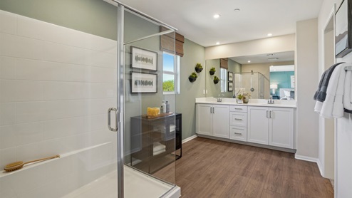 Primary bathroom with dual vanities and shower