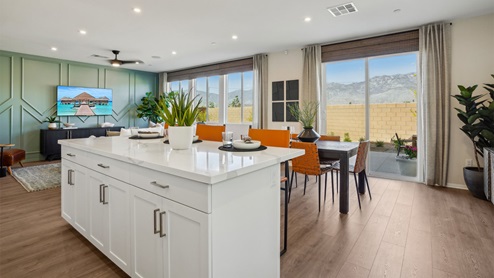 Modern kitchen with white cabinets quartz countertops and stainless steel appliances and dining area with slider to rear yard