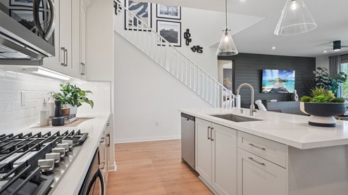 Modern kitchen with light grey cabinets quartz countertops and stainless steel appliances
