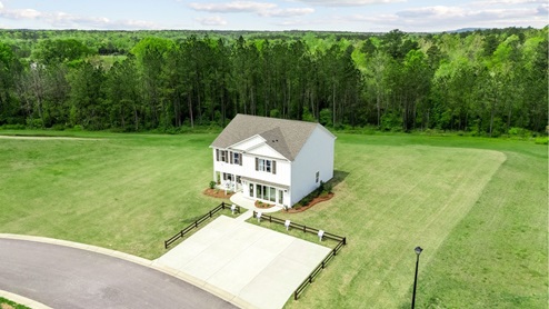 Beautiful exteriror of the penwell model home in saddlewood trails, with white siding, lush green grass and a serene blue sky