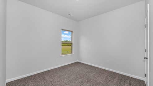 Secondary bedroom with carpet and window