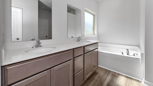Primary bath with stained cabinets and quartz countertops