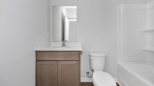Secondary bathroom with stained cabinets and quartz countertops