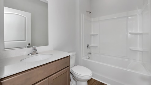 Secondary bathroom with stained cabinets and quartz countertops