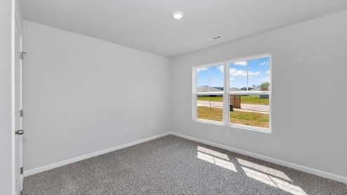 Secondary bedroom with carpet and window