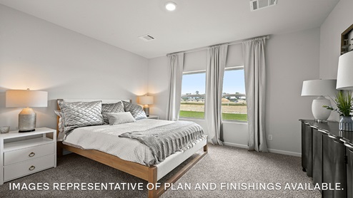 Large primary bedroom with dual windows overlooking the backyard