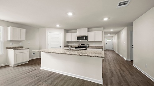White kitchen island with stainless steel appliances with pantry access