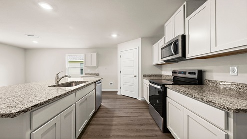 White kitchen island with stainless steel appliances with pantry access