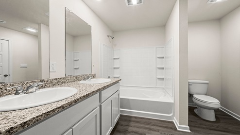 White dual vanities with shower and tub combo and toilet