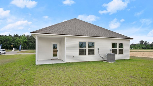 rear of single-story home with four windows, vinyl siding and porch with glass door
