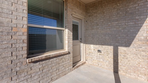 Covered back patio area overlooking spacious backyard