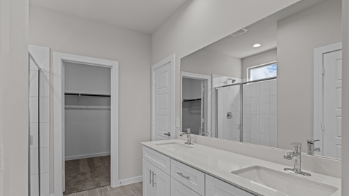 Primary bathroom with cultured marble vanity and personal walk-in closet area