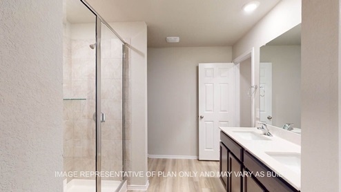 Camden primary bath with dark cabinets and white countertops.