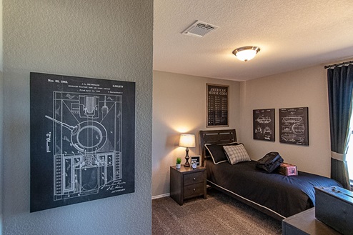 Creekside Hills model home secondary bedroom with twin bed and nightstand and decorative accent pieces.
