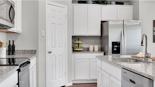 Cedar Trails model home kitchen with white cabinets and granite countertops