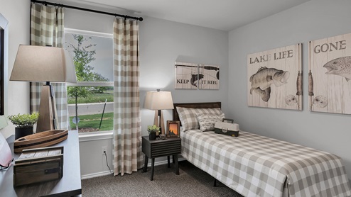 West Canyon Trails Model Home Secondary Bed room decorated with furniture, carpet flooring and light painted walls.