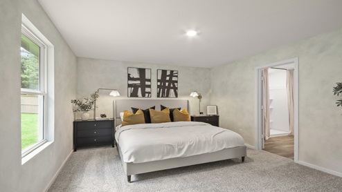 Primary bedroom with windows, white walls, and light carpet.