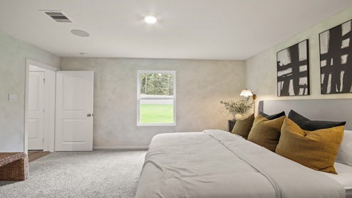 Primary bedroom with windows, white walls, and light carpet.