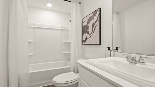 Secondary bathroom with a shower and tub combo, white walls, and vinyl wood flooring.