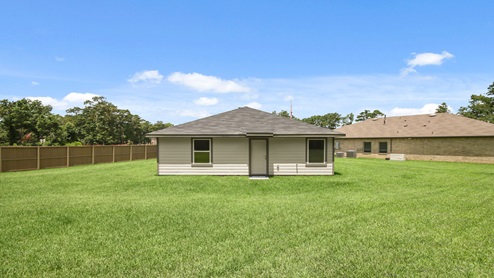 Landscaped backyard with a covered back door.