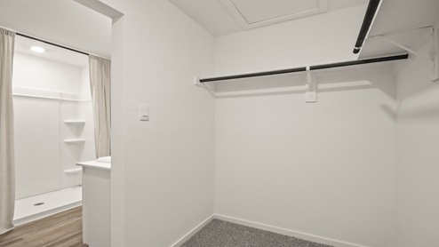 Primary closet with white walls and light carpet.