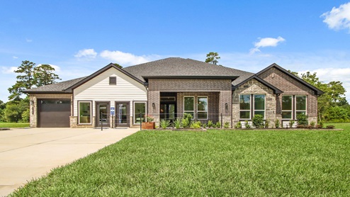 Front of the home with two tone brick, a three-car garage, and double doors.