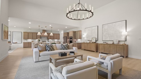 Open living room with large windows, artificial fireplace with stone, white walls, and light vinyl wood flooring.