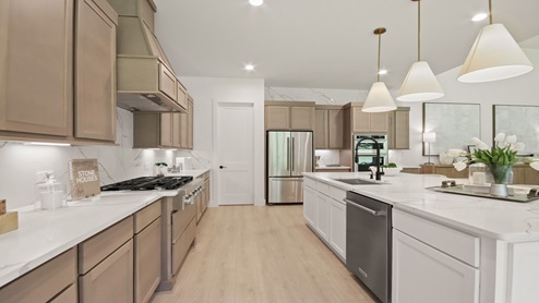 Large open kitchen with an island, upgraded stainless steel appliances, light stained cabinets, white and gray quartz countertops, white walls, and light vinyl wood flooring.