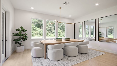 Dining room with backyard access, large windows, white walls, and light vinyl wood flooring.