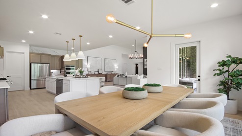 Dining room with backyard access, large windows, white walls, and light vinyl wood flooring.