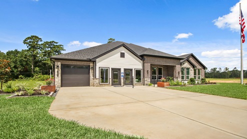Front of the home with two tone brick, a three-car garage, and double doors.
